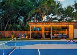 Ein Garten mit Pool, überdachter Terrasse und Holzzaun.