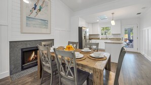 A dining area with a fireplace, a large painting, and a view into the kitchen. - Pool, Pickleball & Putting Green Retreat (Jacksonville Beach)