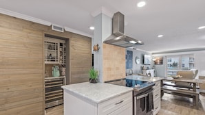 A modern kitchen with a built-in oven, a stainless steel range hood, and a wooden wall panel. - Gorgeous 2 BR Condo with Pool and Ocean Views! (New Smyrna Beach)