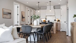 A modern kitchen with white cabinets, a wooden island, and pendant lighting. - Rock Creek at Desert Color: Desert Color Lagoon + Beaches (St George)