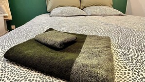 A bed with patterned bedding, a headboard, and two wall-mounted lights.