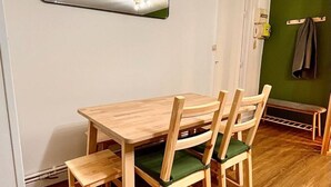A dining area with a wooden table and chairs, a wall-mounted mirror, and a green wall.