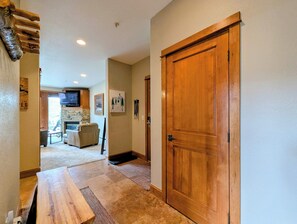 A hallway with a wooden door, a stone fireplace, a television, and a framed picture on the wall.