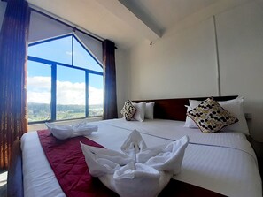 A hotel room with a large bed, a view of the countryside, and a window with curtains. - New Unique View Hotel (Nuwara Eliya)