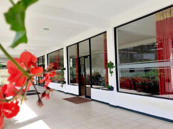 A modern building with large glass windows, a tiled floor, and indoor plants. - New Unique View Hotel (Nuwara Eliya)