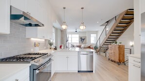 A modern kitchen with white cabinetry, a stainless steel stove, and pendant lighting. - Townhome in the heart of Silverthorne! Walk to everything! (Silverthorne)