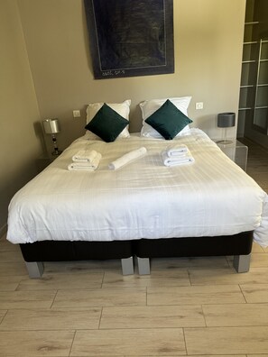 A hotel room with a large bed, two bedside tables, a wall-mounted artwork, and a wooden floor. - Sète, Jolie villa avec piscine à 5 mn des plages (Sète)