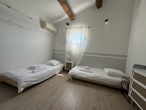 A small, single-room accommodation with two single beds, a wooden floor, and a ceiling fan. - Sète, Jolie villa avec piscine à 5 mn des plages (Sète)