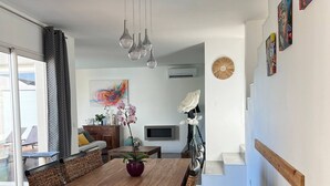 A modern dining area with a wooden table, woven chairs, and hanging pendant lights.