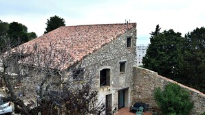 Un edificio in pietra con tetto in tegole, un piccolo patio con tavolo e sedie, e vista sulla campagna circostante.
