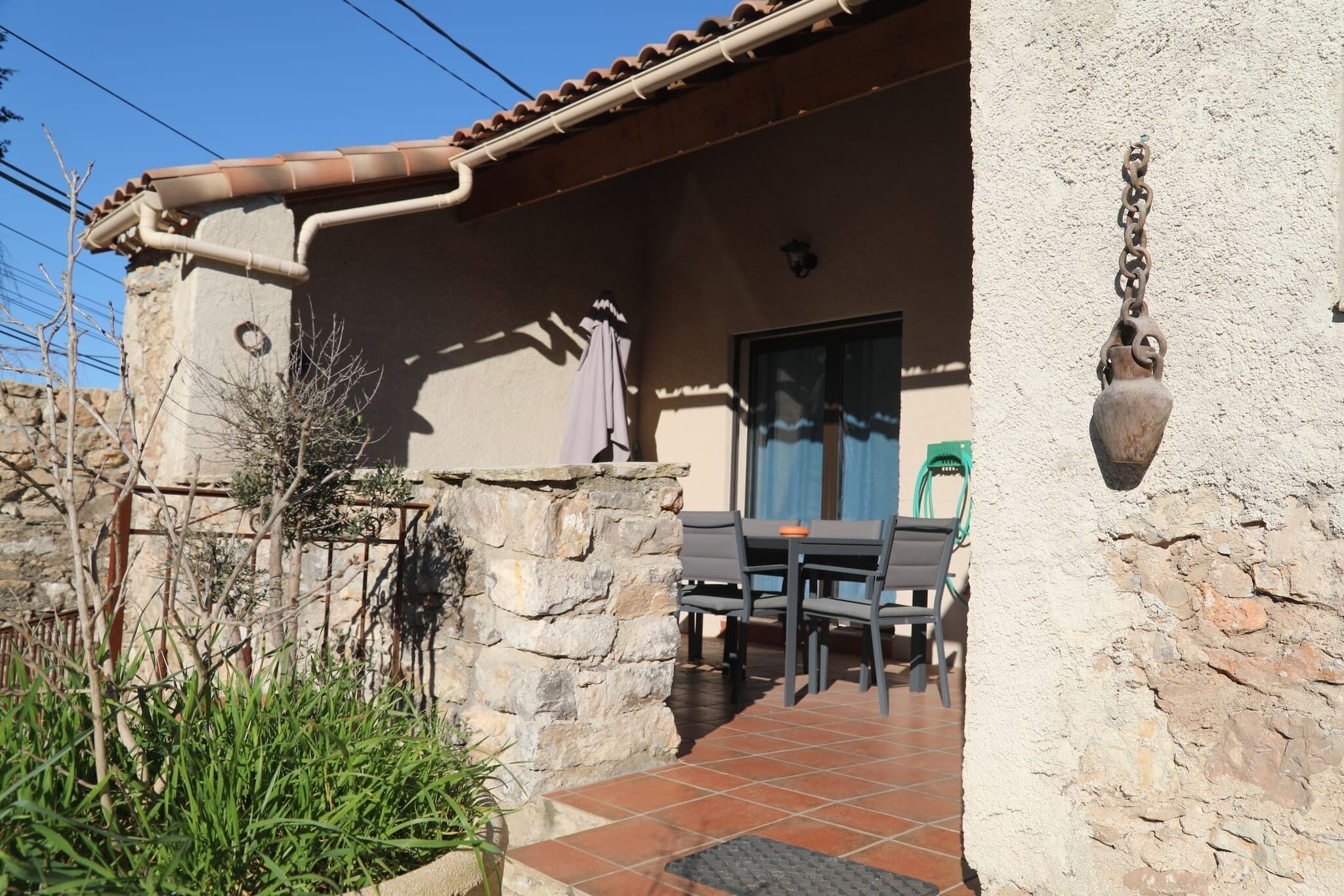 Una zona patio con pareti in pietra, pavimento piastrellato e tavolo con sedie.