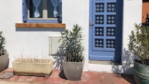 Een gebouw met een blauwe deur, een raam met gordijnen en plantenbakken.