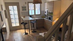 Een compacte keuken met een eethoek, een raam met uitzicht, en een trap naar een ander niveau.