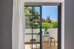 A balcony with a table and chairs, a potted plant, and a view of a garden with trees and flowers. - Quarteira "v.t. Lovely" T2 (Quarteira)