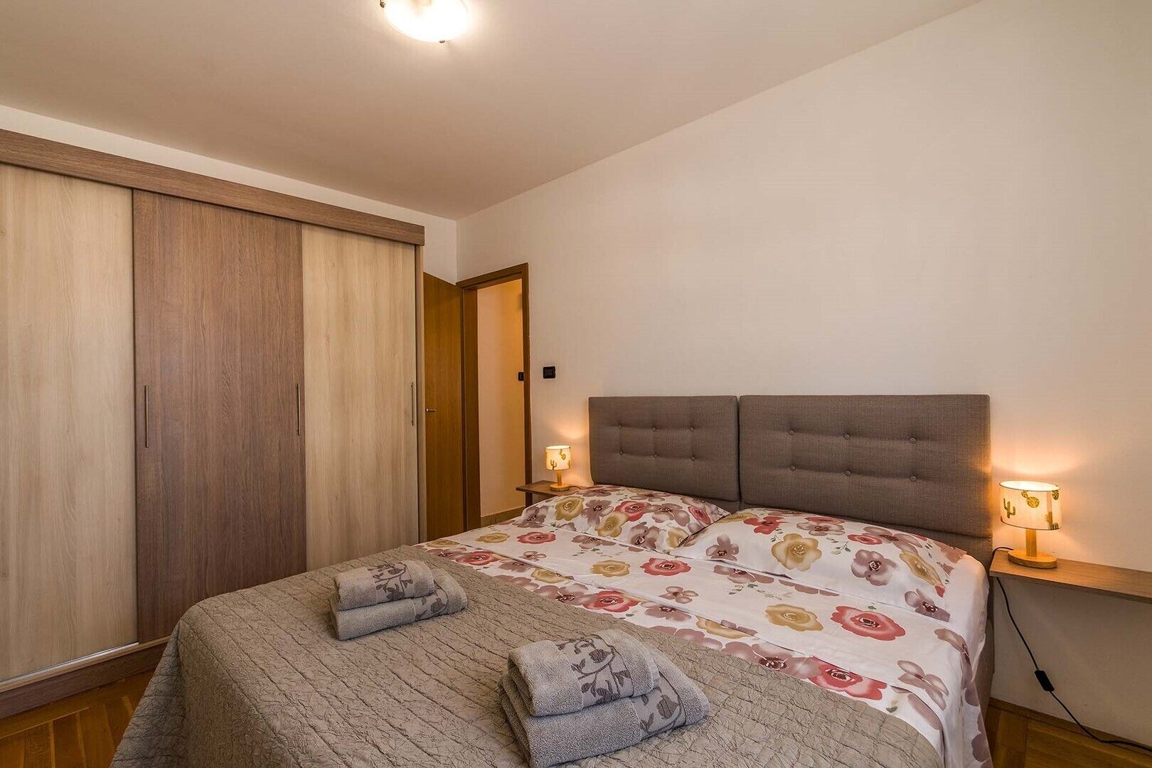 Un dormitorio con cama, armario y dos lámparas de noche.