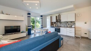 A modern living room with a large TV, a sofa, and a dining area with a table and chairs.