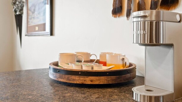 A coffee machine with a tray of cups and a decorative bowl on a countertop. - Newly Built Rustic Cabin w/ Mountain & Pond Views (Kalispell)