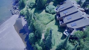 Vista aérea de una zona residencial con varias casas, una playa y abundante vegetación.
