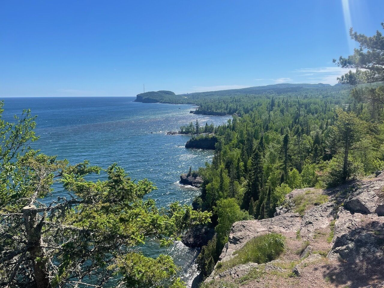 Eine Küstenlandschaft mit freiem Blick auf das Meer, dichtem Wald und felsigem Gelände.