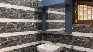 A bathroom with a white pedestal sink, a mirror, and a shower. - Royalwood City Inn (Biratnagar)