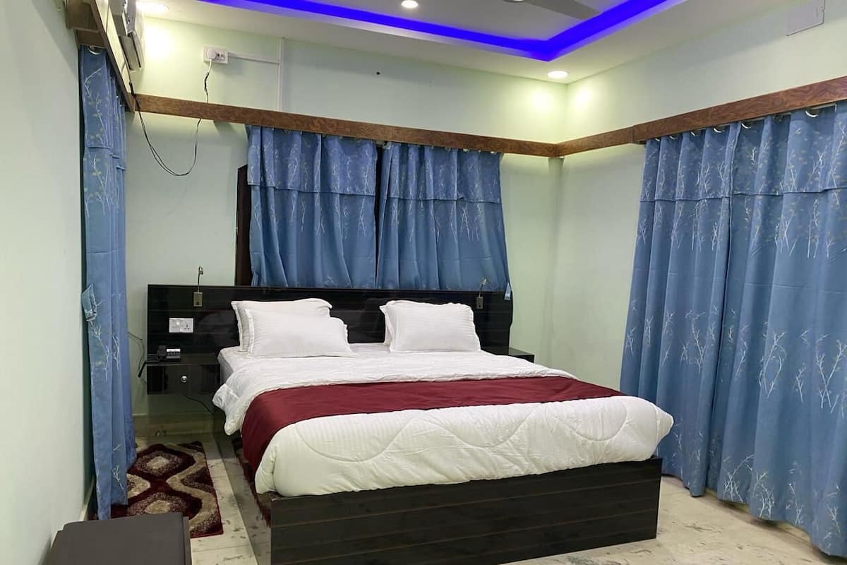 A bedroom with a bed, curtains, a bedside table, and a nightstand.