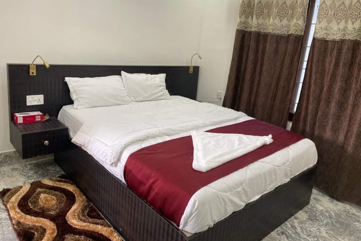 A neatly made bed with white and red bedding, a dark headboard, and a brown patterned rug.