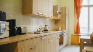 Een moderne keuken met houten kastjes, een waterkoker, een koffiezetapparaat en een raam met oranje gordijnen.