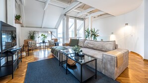 A modern living room with a sofa, a glass coffee table, a TV, and various plants. - Charles Apartments in Old Town Prague (Prague)