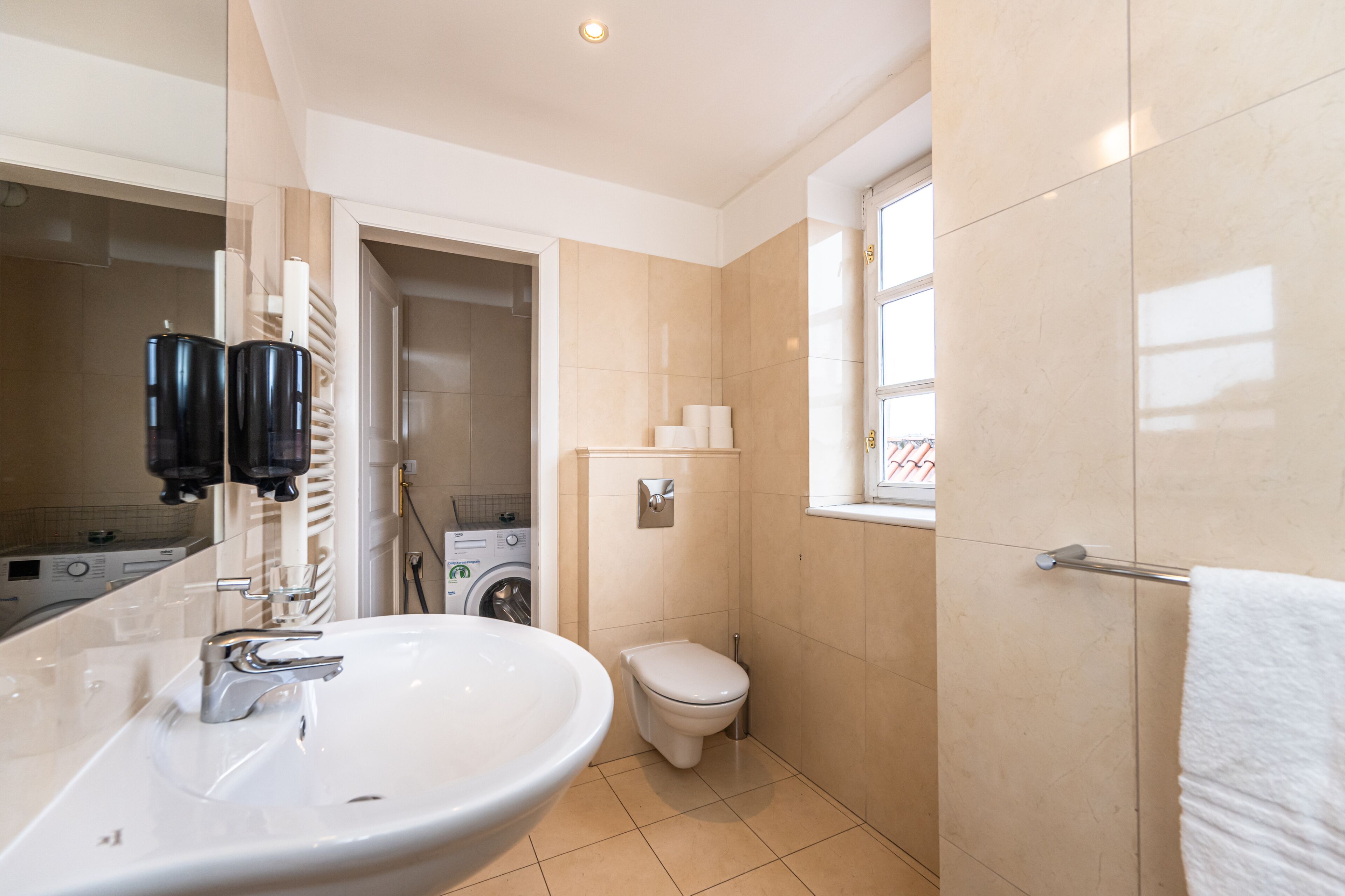 Un baño moderno con lavamanos amplio, inodoro y ventana.