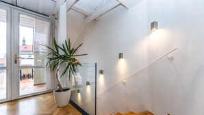 A modern interior with a wooden staircase, a potted plant, and a glass door leading to an outdoor area. - Charles Apartments in Old Town Prague (Prague)