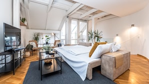A modern hotel room with a large bed, a TV, a desk, and multiple potted plants. - Charles Apartments in Old Town Prague (Prague)