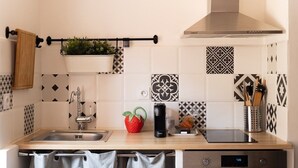 A modern kitchen with a stainless steel sink, a black electric kettle, a red fruit bowl, and a digital clock. - Apartment Roof Top with spa (Bastia)