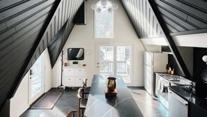 A modern kitchen with a central island, a dining area, and a large window. - Modern A-Frame | Mountain Views | Evergreen (Evergreen)