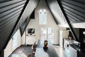 A modern kitchen with a central island, a dining area, and a large window. - Modern A-Frame | Mountain Views | Evergreen (Evergreen)