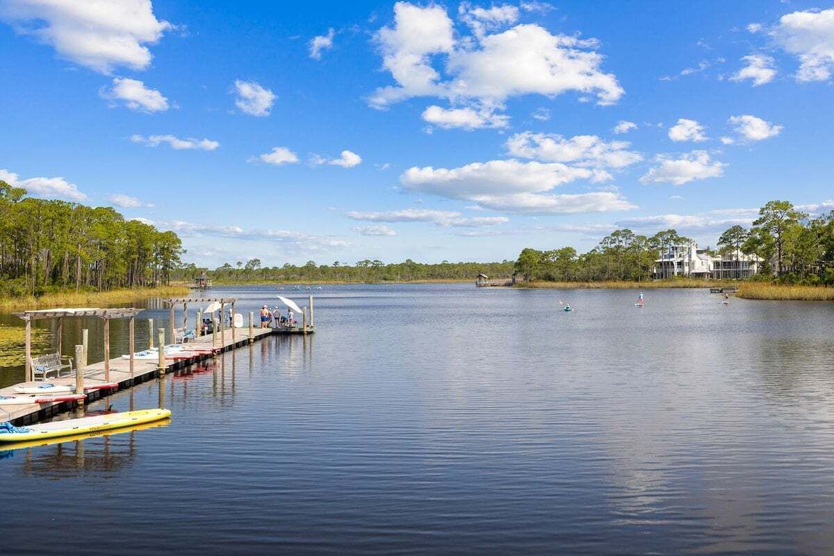 A calm lake with a dock and a white building in the background.