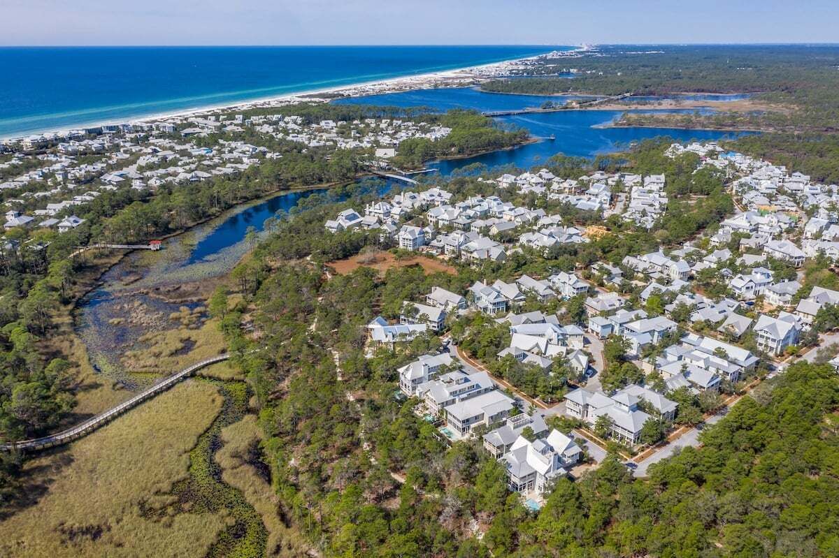 Vue aérienne d’une zone résidentielle côtière, avec des maisons, un pont et une plage.