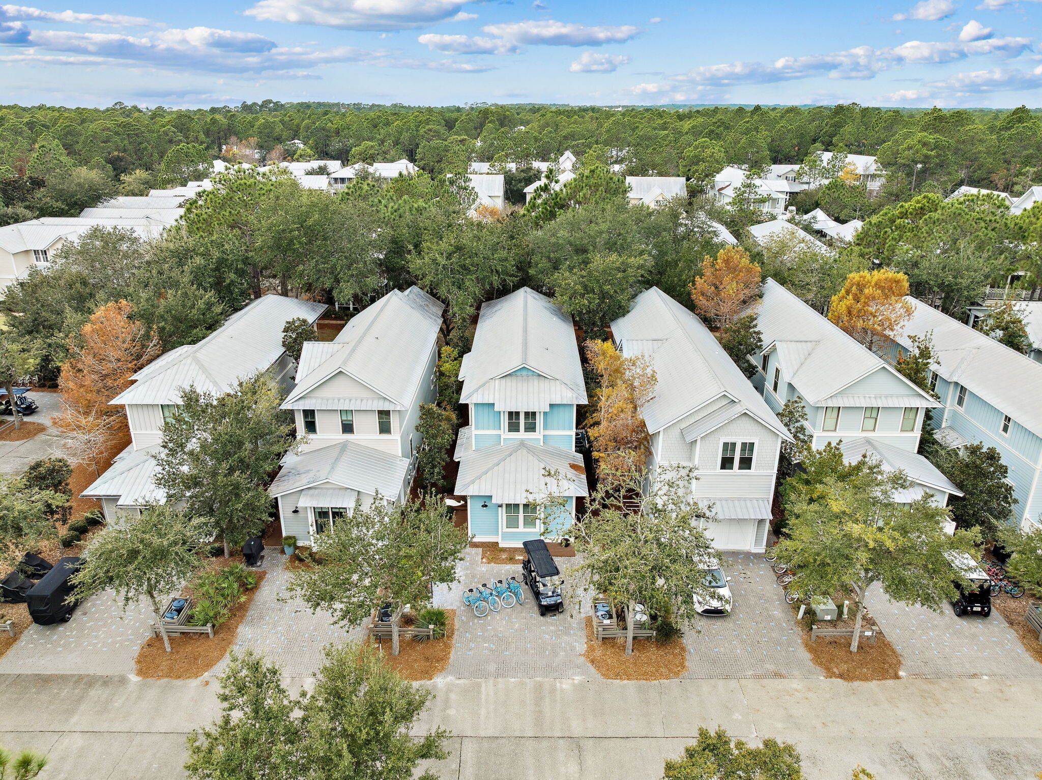 A residential area with multiple houses, a paved parking area, and trees.