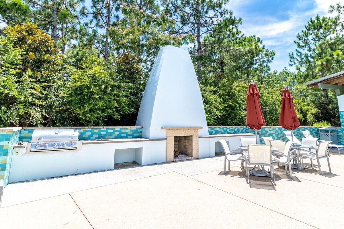 Une terrasse extérieure équipée d’un barbecue, d’un coin salon et de parasols.
