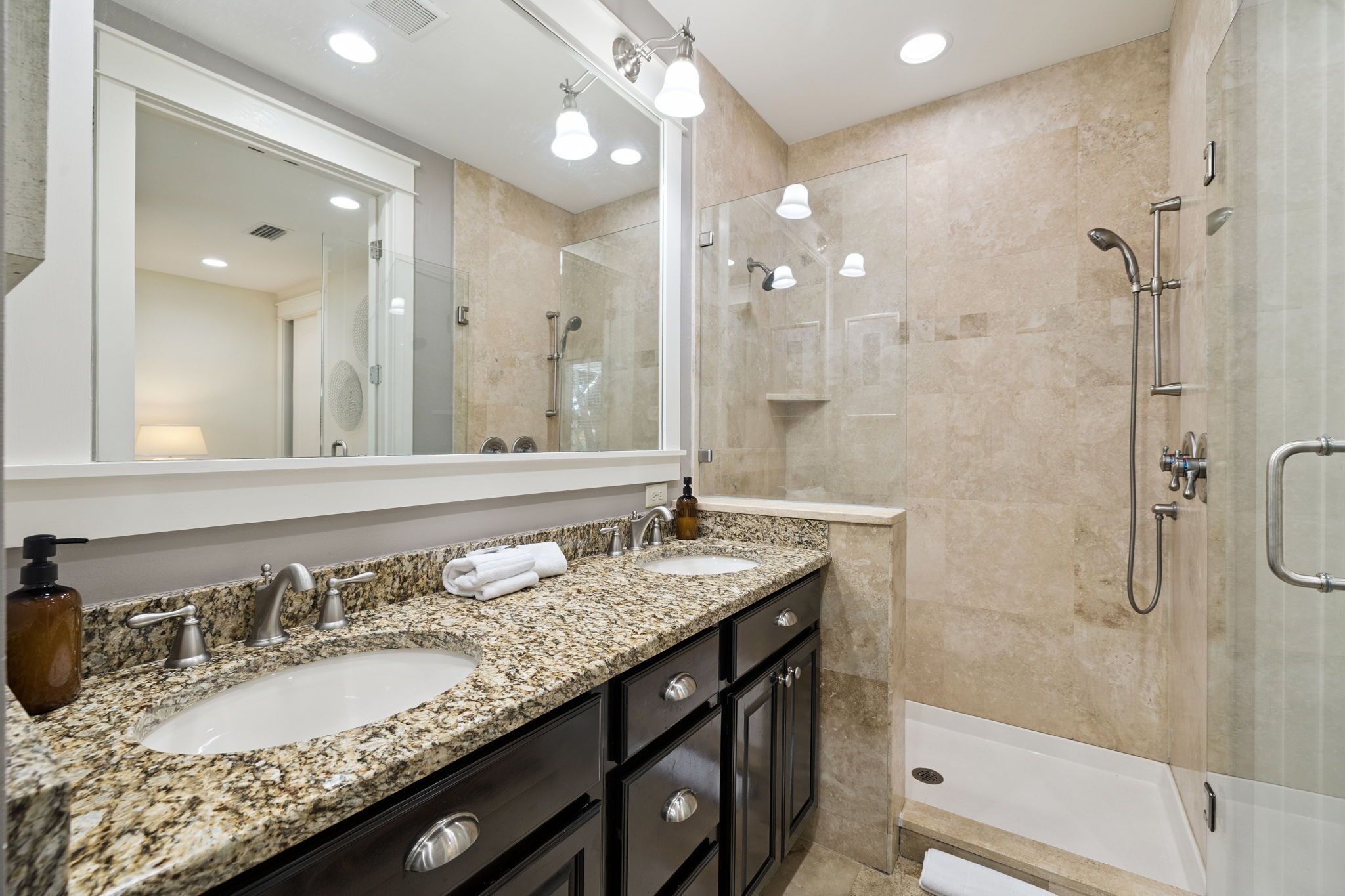 A modern bathroom with two sinks, a large mirror, a shower, and a bathtub.