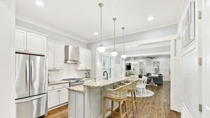 A modern kitchen with white cabinetry, stainless steel appliances, and a central island with bar stools.