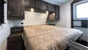 A bedroom with a bed, dark wooden cabinets, and a window.