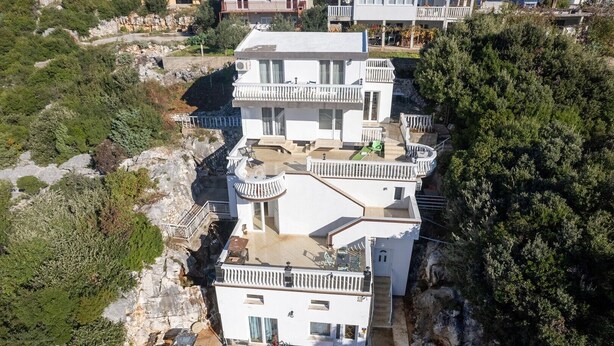 Un edificio de varios pisos con balcones, un patio y vistas del paisaje circundante.