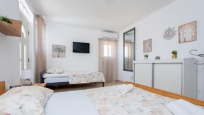 Un dormitorio con dos camas, televisión, espejo y un mueble pequeño.