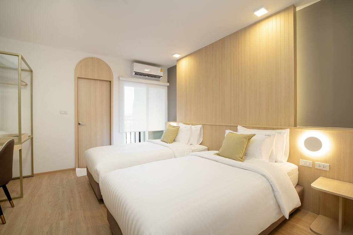 A hotel room with two beds, a desk, and a wardrobe.
