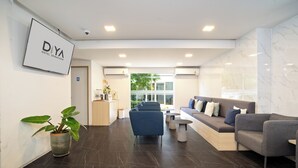 Un moderno vestíbulo de hotel con mostrador de recepción, zona de estar y una planta en maceta.