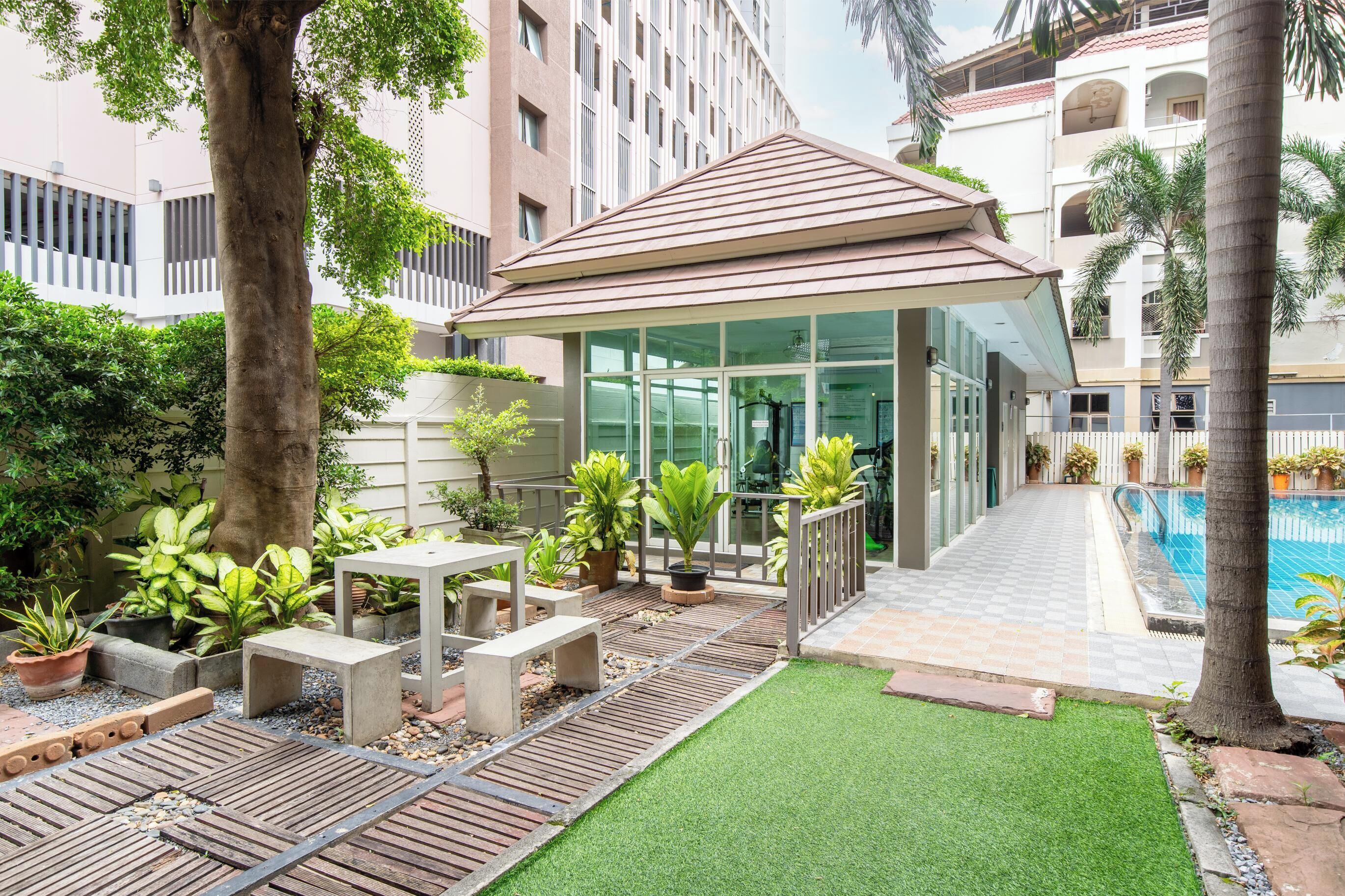 Un patio con piscina, mobiliario exterior y una zona cubierta.