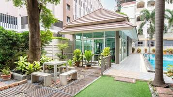 Un patio con piscina, mobiliario exterior y una zona cubierta.