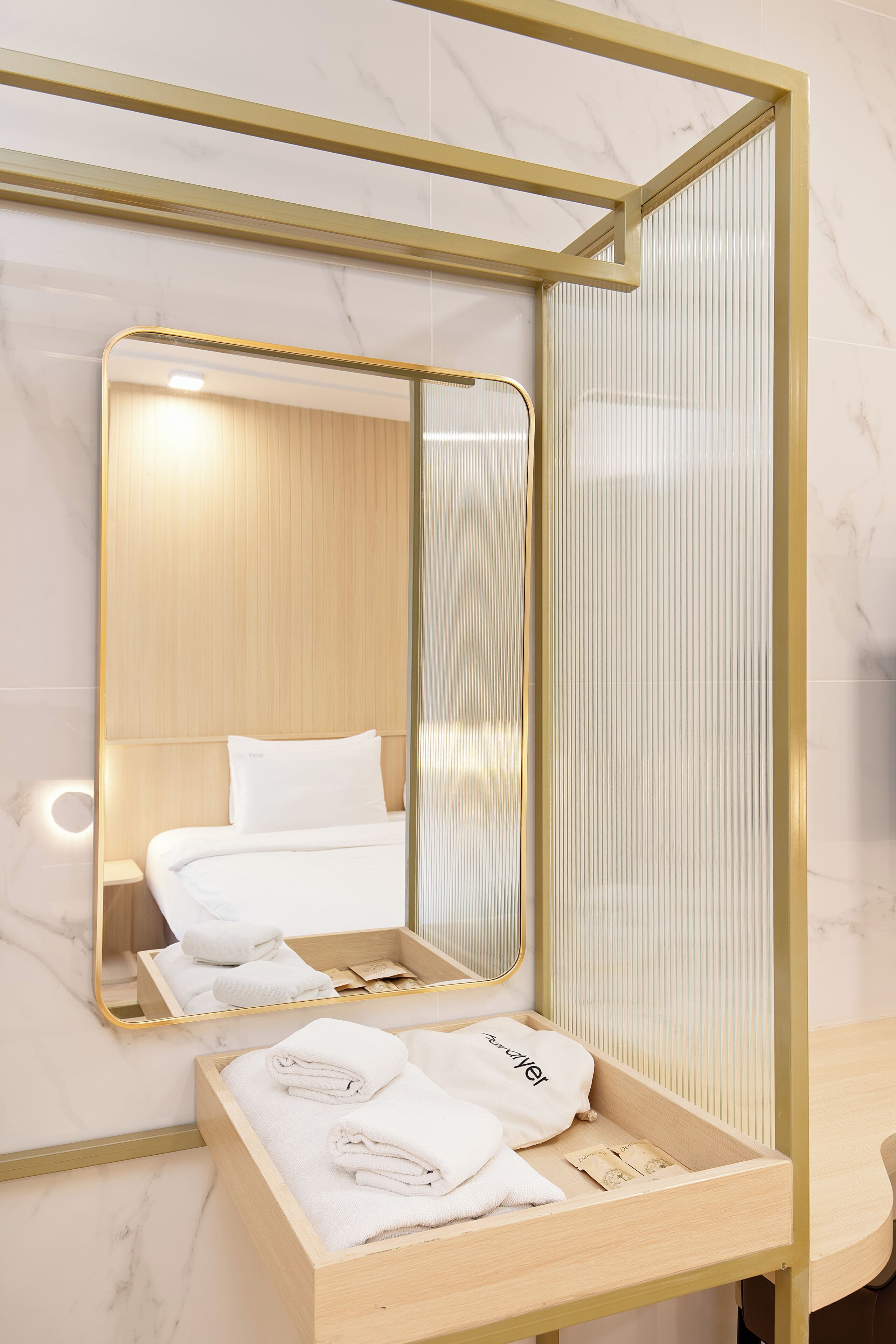 Un baño de hotel con piso de mármol, tocador de madera con espejo y toallas ordenadas.