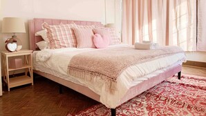 Ein Schlafzimmer mit einem Bett, Nachttischen, Vorhängen an einem Fenster und einem gemusterten Teppich.