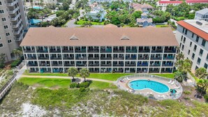 Um hotel com vários andares, piscina no terraço e rodeado por vegetação e edifícios residenciais.